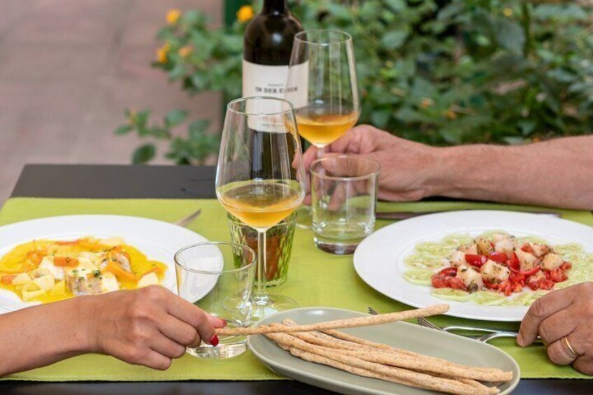 A table with two plates of food, a bottle of wine, and glasses of wine. 3