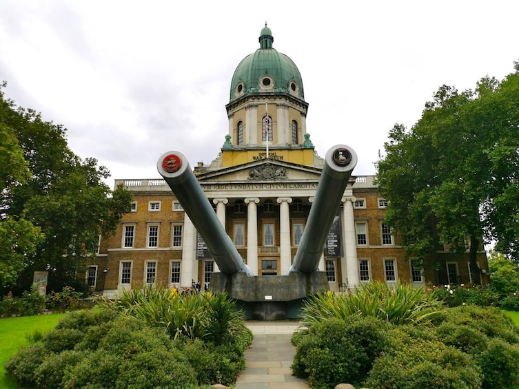 Un bâtiment historique surmonté d’un dôme vert et flanqué de deux gros canons à l’avant. 1