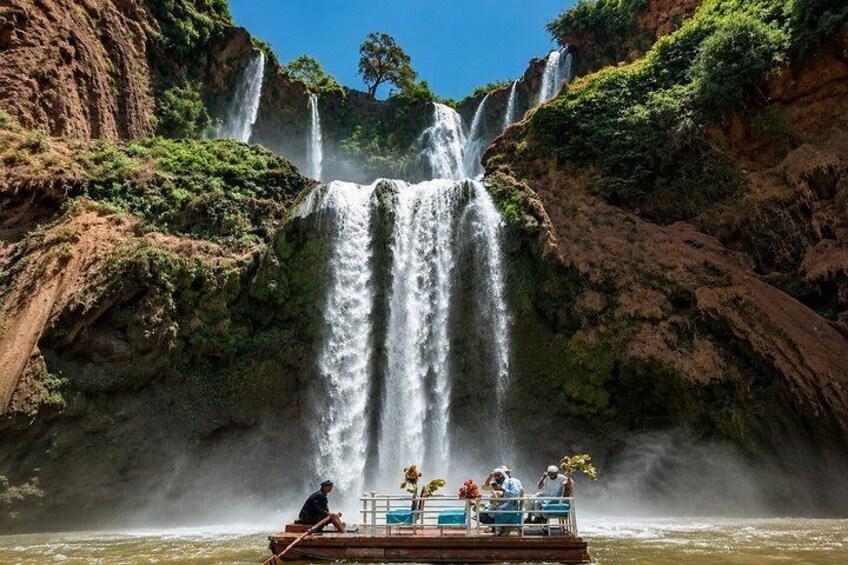 A boat with people on a river with a waterfall in the background. 3