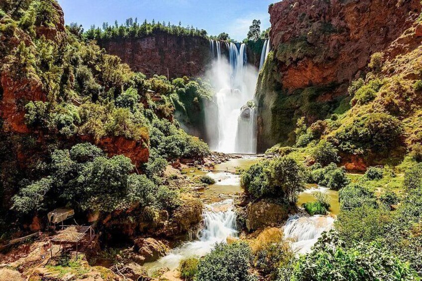 A waterfall cascading down a rocky cliff surrounded by lush greenery. 2