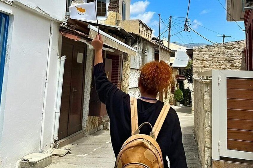 Una persona con una mochila caminando por una calle estrecha con edificios de piedra y una bandera en un balcón. 2