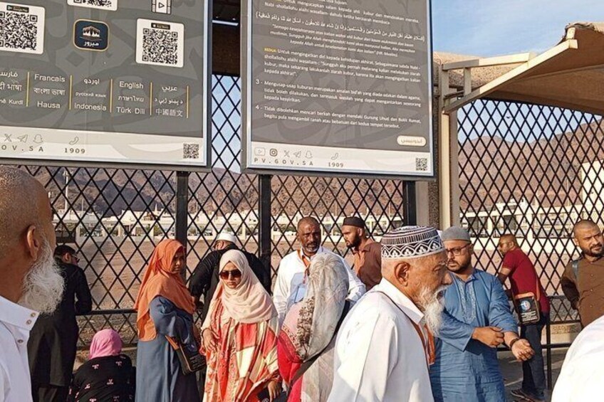 A group of people standing in front of a fence with informational signs. 1