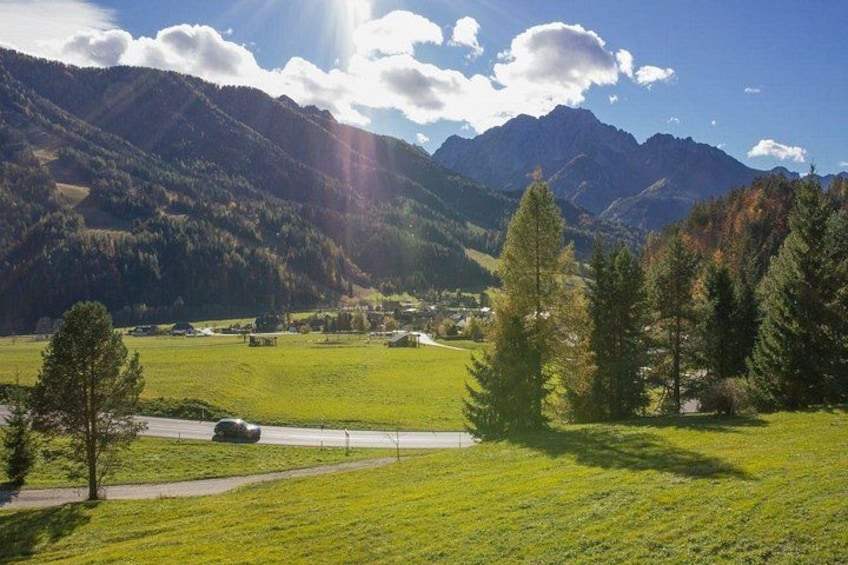 A mountainous landscape with a clear sky, a road, and a green field. 2