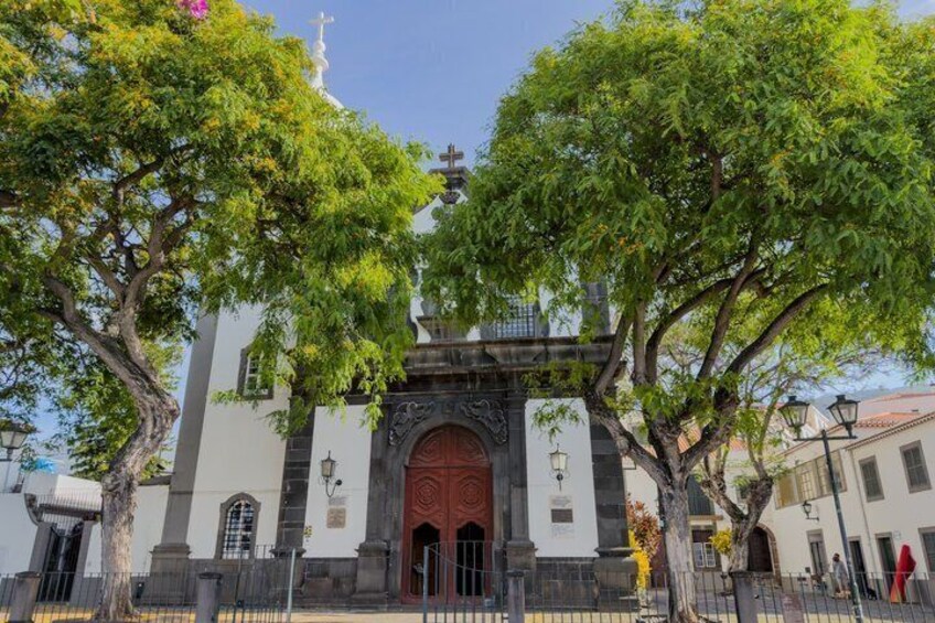 A church with a red door, surrounded by trees and a white building with a cross. 1
