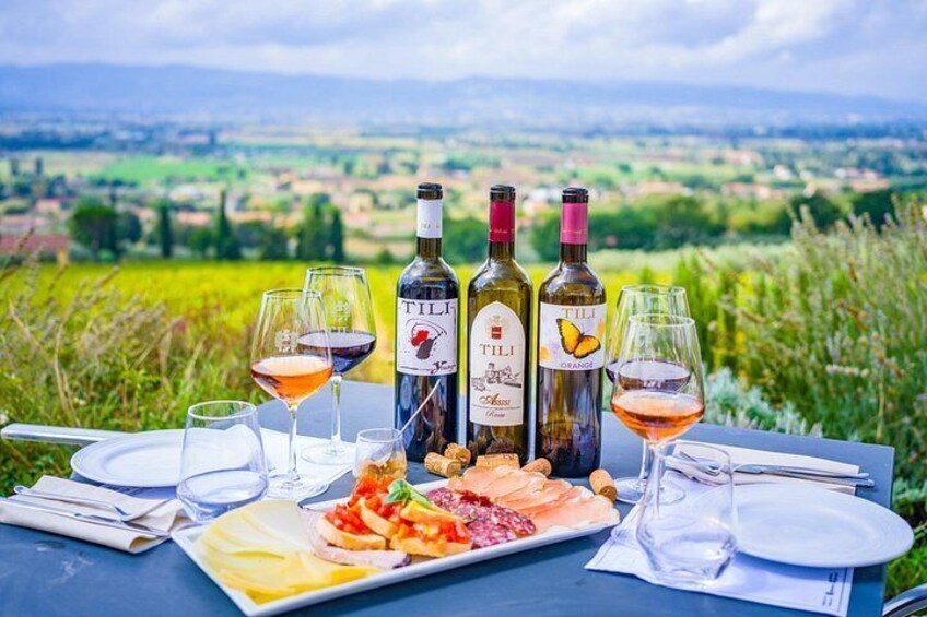A table set outdoors with wine bottles, glasses, and a plate of food. 1