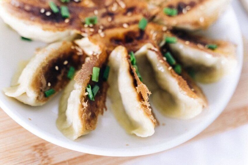 A plate of dumplings garnished with sesame seeds and chopped green onions. 5