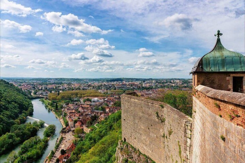 A river, a cityscape, and a historic fortification with a green dome. 1
