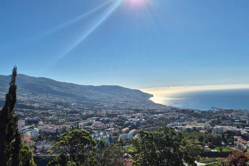 A coastal cityscape with a clear sky, a mountain in the background, and a view of the sea. 2