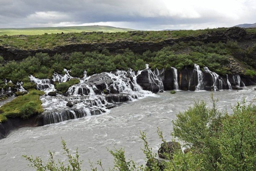 A river with multiple waterfalls, surrounded by lush greenery and hills in the background. 4