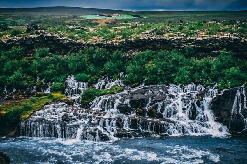 A waterfall cascading over rocks in a lush green landscape. 2