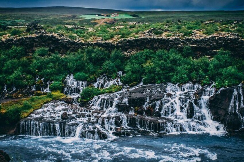 A waterfall cascading over rocks in a lush green landscape. 2