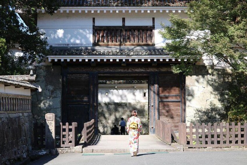 A traditional Japanese building with a wooden gate and a person in traditional attire walking towards it. 3