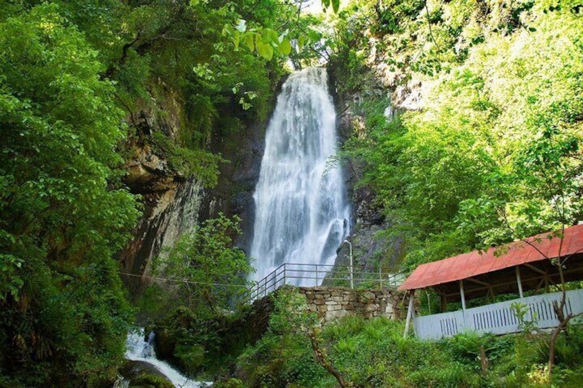 A waterfall cascading down a rocky cliff surrounded by lush greenery. 2