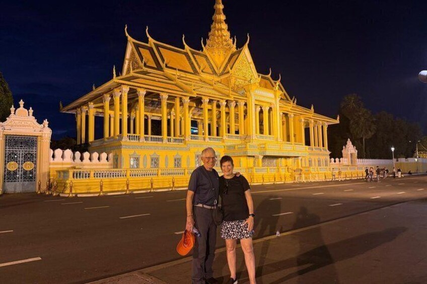 A person and a woman standing in front of a brightly lit temple with ornate architecture. 5