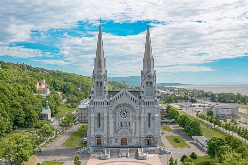 A large church with two tall spires, surrounded by greenery and a clear sky. 1