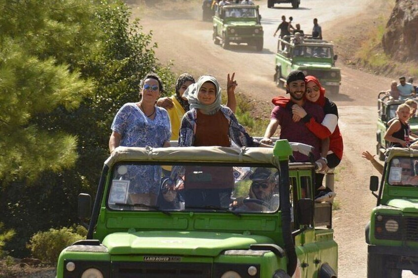 A group of people on a green off-road vehicle driving on a dirt road. 4