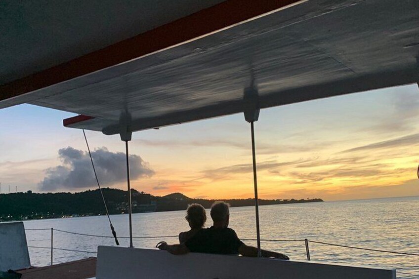 A sunset over water with a boat and a person. 1