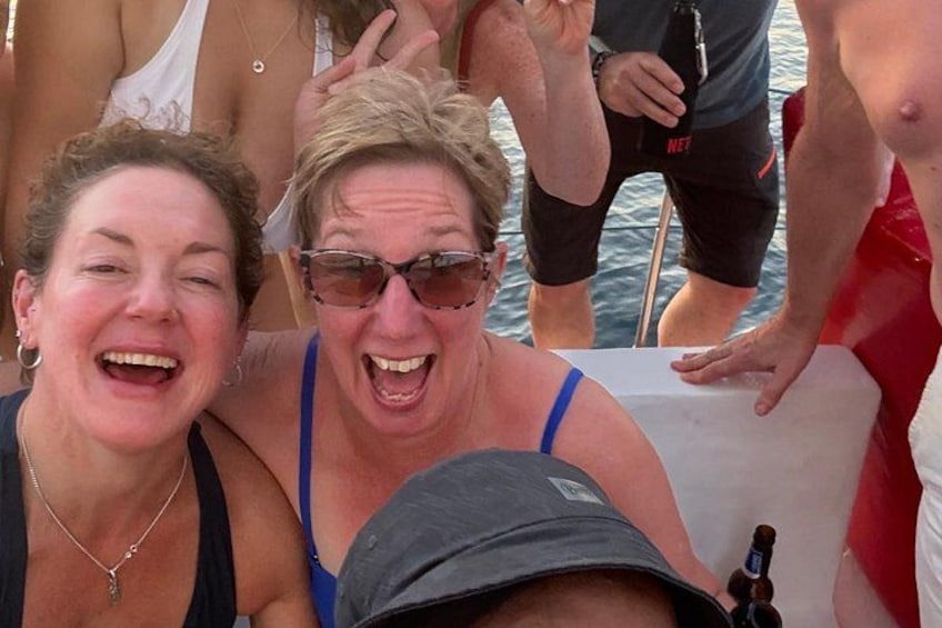 People on a boat, some wearing swimwear, and a bottle of beer on the table. 3
