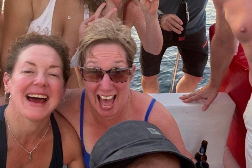 A group of people on a boat, some wearing swimwear, with a bottle of beer on the table. 2