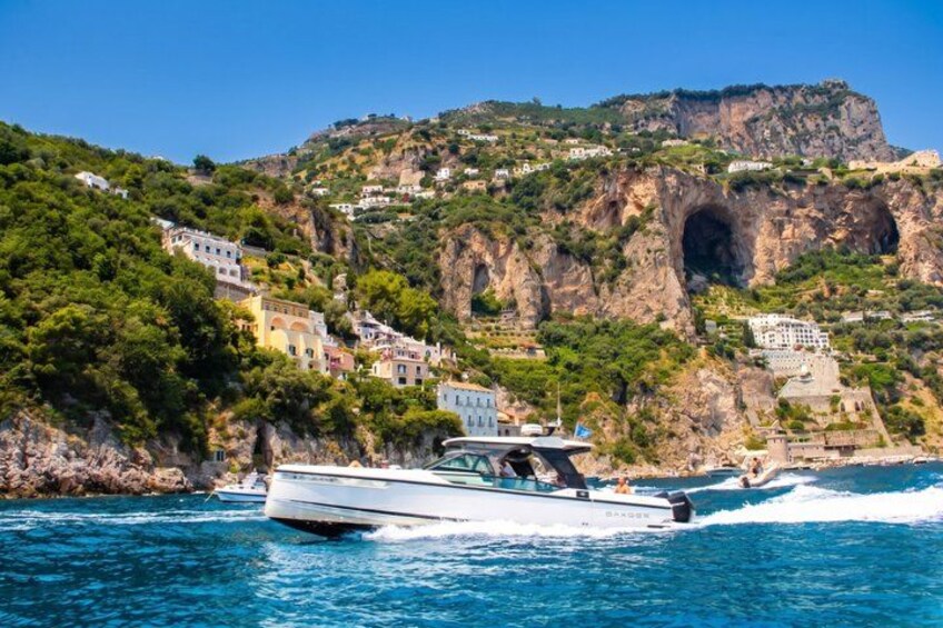 A boat on a clear blue sea with a mountainous coastline in the background. 3
