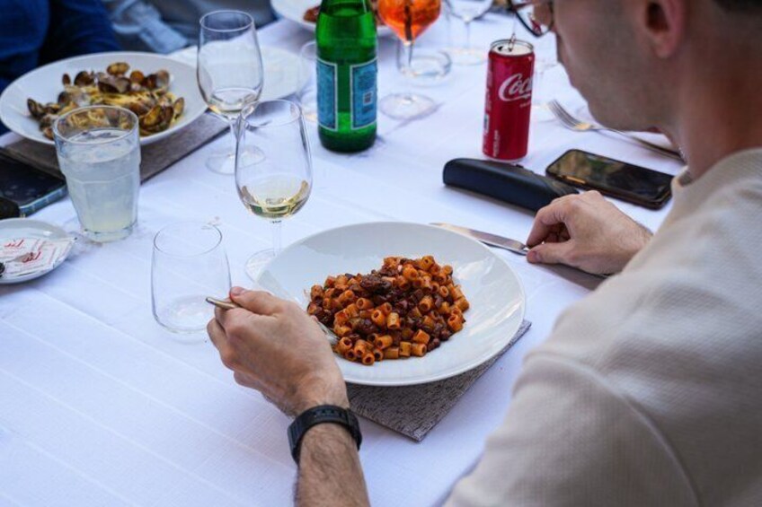 A person dining at a table with a plate of pasta, a glass of white wine, and a can of Coca-Cola. 5