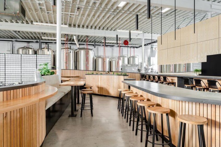 A modern bar with wooden accents, metal bar stools, and stainless steel appliances. 1