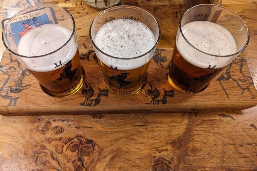 Three glasses of beer on a wooden tray with a beer tap and coaster. 4