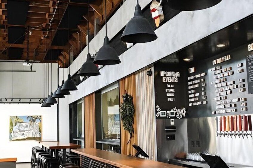 A modern interior with hanging pendant lights, a wooden table, and a wall displaying event schedules. 3