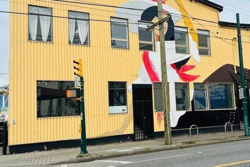 A yellow building with a large white and red mural, a traffic light, and a sign on the side. 5