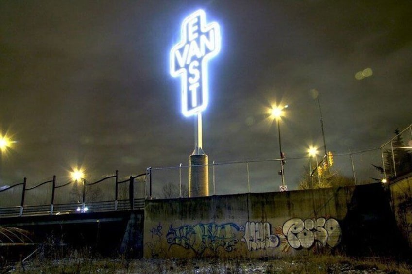 A brightly lit street sign with graffiti on a wall. 2