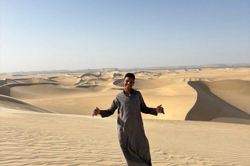 A person standing in a desert with sand dunes in the background. 1
