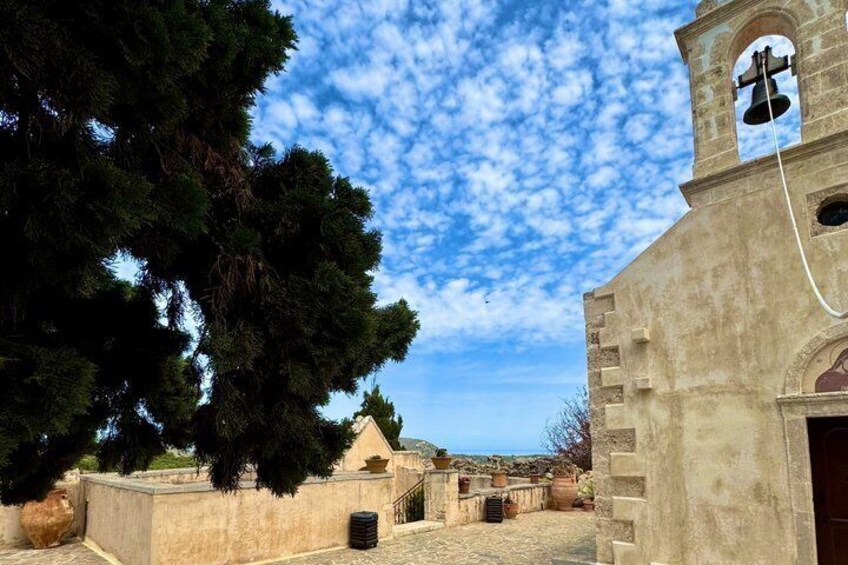 A church with a bell tower, a stone wall, and a large tree. 3