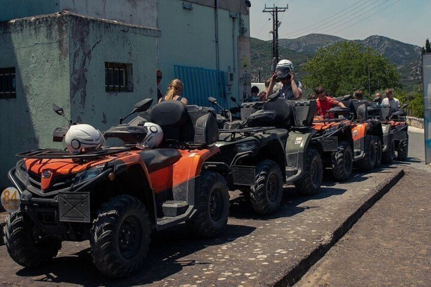 A row of ATVs parked on a street with buildings and hills in the background. 5
