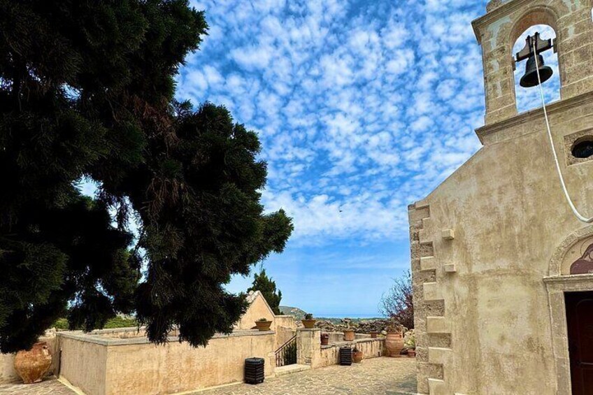 A church with a bell tower, a stone wall, and a large tree. 3
