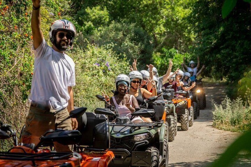 A group of people on ATVs on a dirt path surrounded by greenery. 1