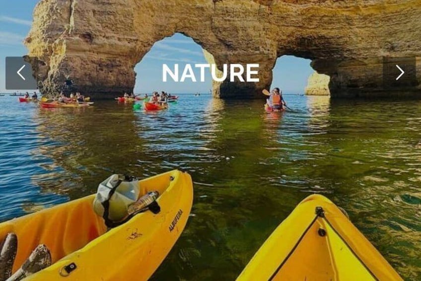 Kayaks on calm water with a large rock arch in the background. 5