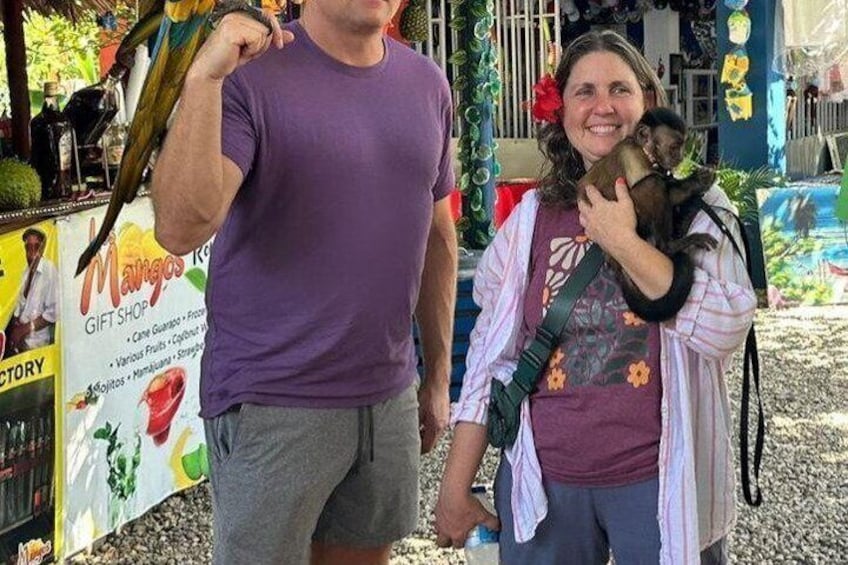 A person holding a monkey, another person with a water bottle, and a sign for a gift shop. 1