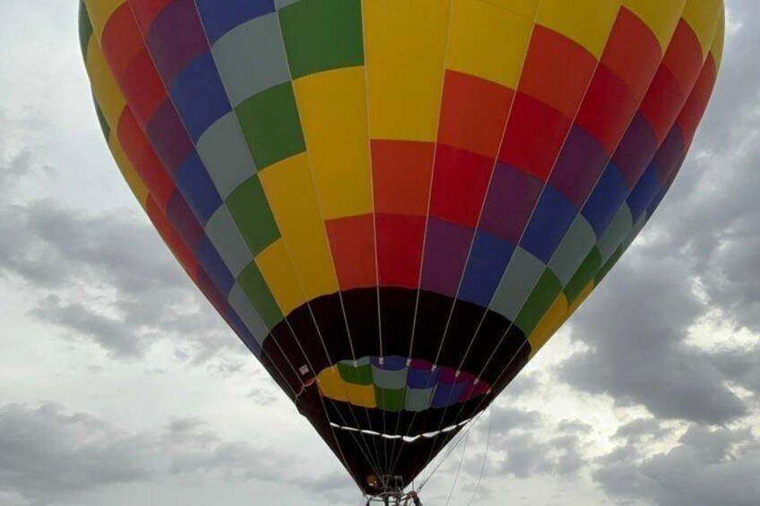 A hot air balloon with a multicolored pattern against a cloudy sky. 4