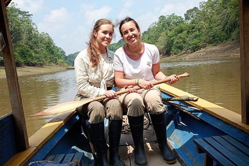 Two people in a boat on a river surrounded by greenery. 1