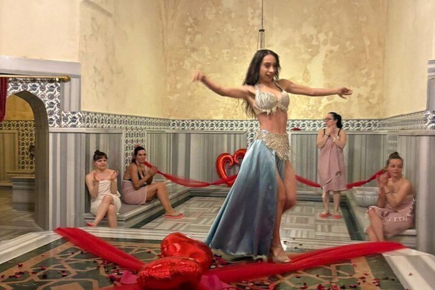 A woman performing a belly dance in a room with ornate walls and a patterned floor. 5