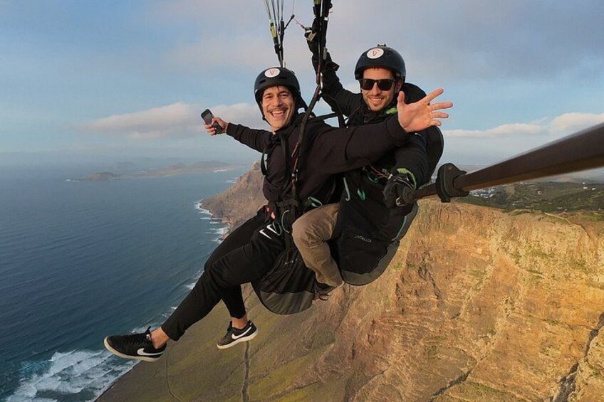 Two people bungee jumping from a cliff overlooking the ocean. 5