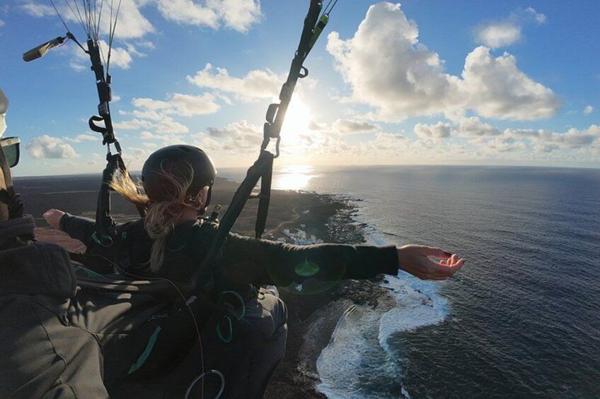 A person paragliding over the ocean with a clear sky and clouds. 1