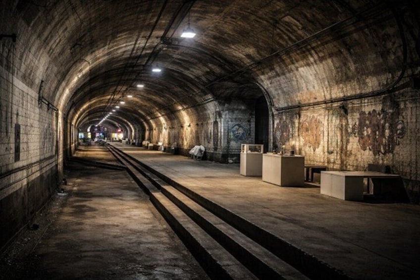 A dimly lit, arched tunnel with concrete walls and a central walkway. 2