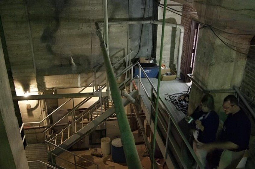 An industrial setting with a staircase, metal railings, and a person using a mobile device. 2