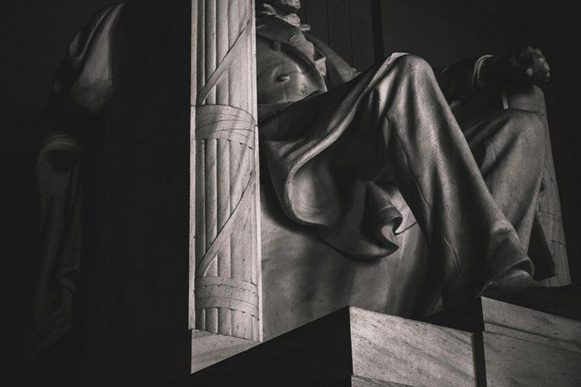 A sculpture of a reclining figure with draped clothing, set against a column. 5