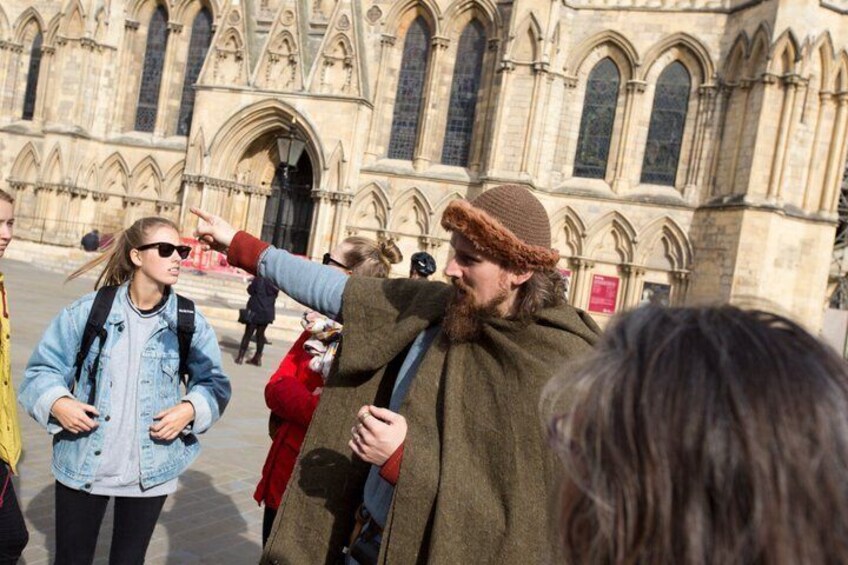 A group of people in front of a historic building with pointed arches and detailed stonework. 5