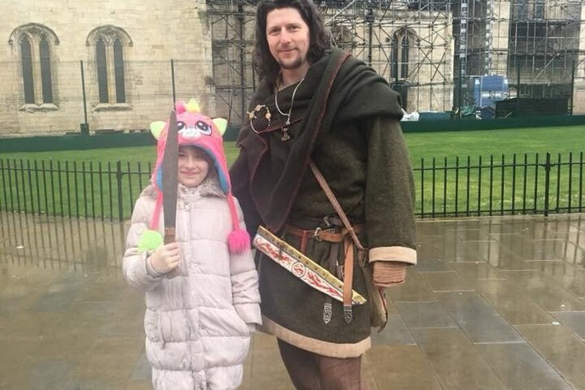 A person in a costume with a sword and a child in a pink outfit with a hat. 2