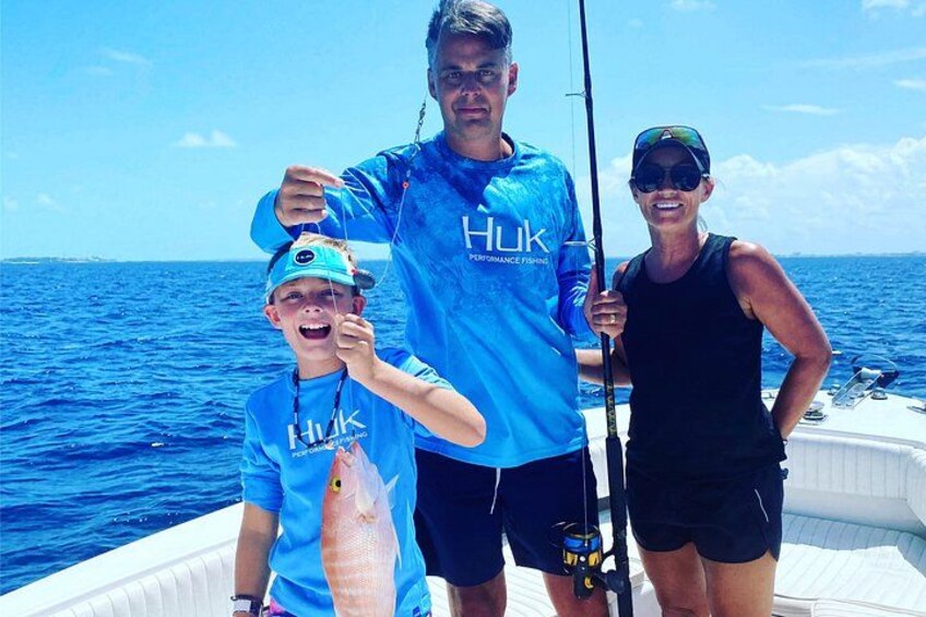Three people on a boat holding a fish. 1