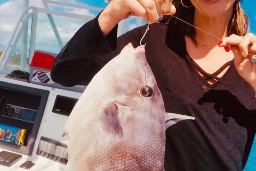 A person holding a fish with a boat in the background. 4