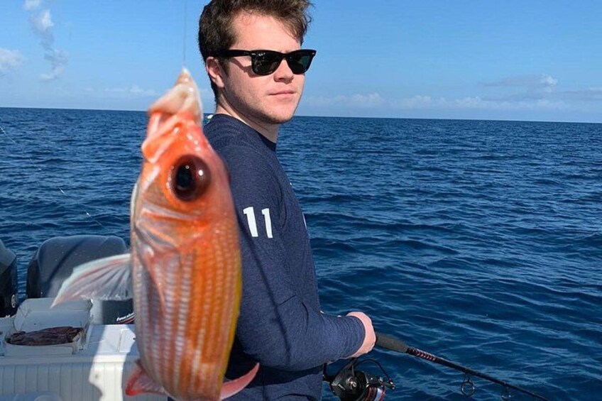 A person holding a fish on a boat with the ocean in the background. 2